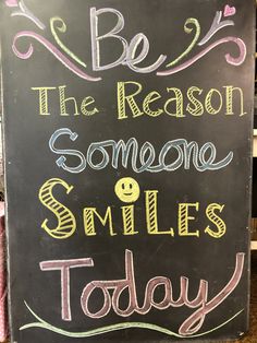 a chalkboard sign that says be the reason someone smiles today with smiley faces on it