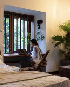 a woman sitting at a desk in front of a bed