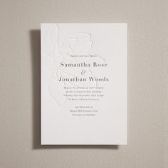 an elegant wedding card with the word's initials and flowers on it, in white paper