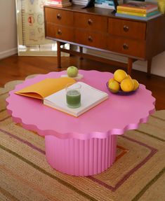 a pink coffee table with a book and some lemons on the table next to it