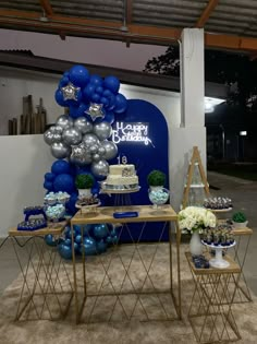 a blue and silver birthday party with balloons, cake and dessert table set up for it