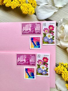 two envelopes with stamps on them next to yellow flowers and white tulips