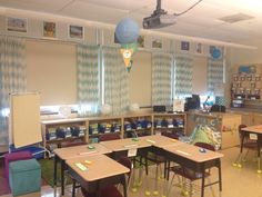 an empty classroom with desks and chairs in front of the bookshelves filled with school supplies