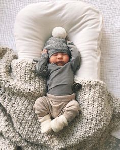 a baby laying on top of a bed under a blanket