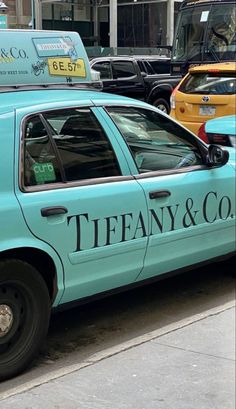 a blue taxi cab is parked on the side of the street in front of other cars