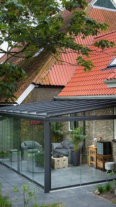 a glass enclosed patio area in front of a house with red tiled roof and brick walls