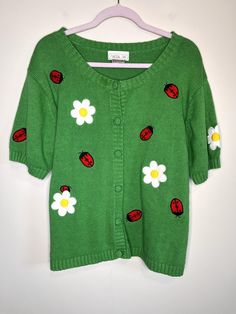 a green sweater with ladybugs and daisies on it