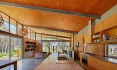 an open kitchen and dining area with wood paneled walls, floor to ceiling windows, and large sliding glass doors