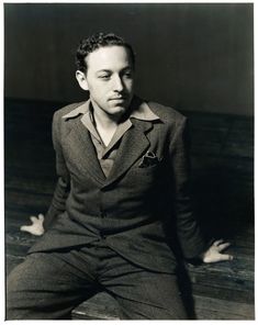 black and white photograph of a man in suit sitting on the floor with his legs crossed