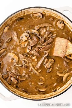 a pot filled with mushroom stew and a wooden spoon