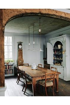 a large wooden table sitting in the middle of a living room next to a book shelf