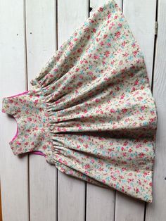 an old dress is laying on the floor next to a white fence with pink and blue flowers