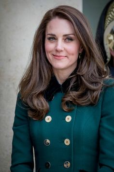 a woman in a green coat smiles at the camera