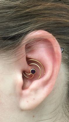 a woman's ear is shown with two gold spirals