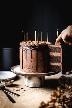 a chocolate cake sitting on top of a wooden table next to plates and spoons