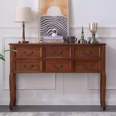 a wooden dresser sitting next to a lamp on top of a table