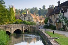 an old stone bridge over a river in the middle of a village with houses on either side