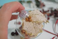 a hand holding a glass ornament with leaves on it