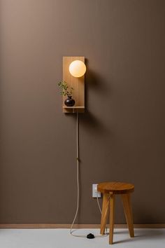 a small wooden table sitting next to a lamp on a wall with a plant growing out of it