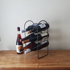 several bottles of wine are stacked in a metal holder on top of a wooden table