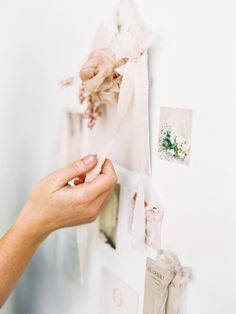 a person is holding something in their hand on the wall next to pictures and flowers