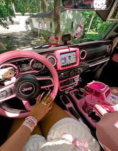 a woman sitting in the driver's seat of a car with pink interior and steering wheel