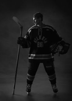 an ice hockey player is posing for a black and white photo with his stick in hand