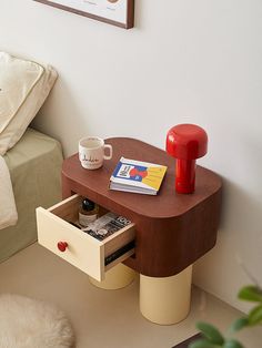 a coffee table with magazines and a cup on it next to a bed in a bedroom