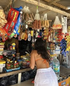 a woman standing in front of a store filled with food