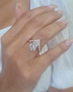 a woman's hand with a diamond ring on top of her finger and an engagement band