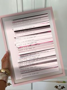 a person holding up a framed piece of paper with pink and black strips on it