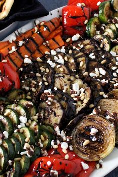 grilled vegetables on a platter with nuts and seasoning sprinkles