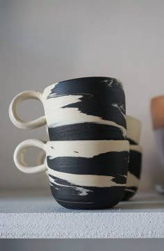 two black and white cups sitting on top of a shelf