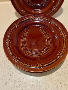 two brown plates sitting on top of a counter next to each other with decorative designs