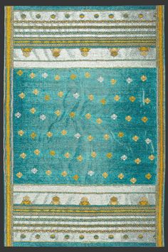 an old blue and yellow rug with small flowers on the border, in front of a black background