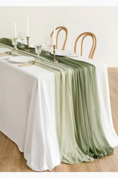 the table is set with white and green linens, gold place settings and candles