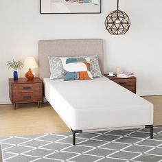 a white bed sitting on top of a wooden floor next to a dresser and lamp