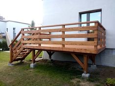 a wooden bench sitting on top of a lush green field next to a white building