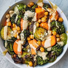 a white bowl filled with broccoli, carrots and chickpeas covered in dressing