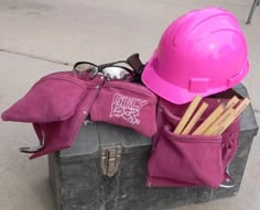 a hard hat, glasses and other items are sitting on top of a suitcase outside