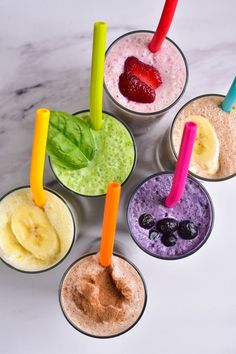 four cups with different types of smoothies in them