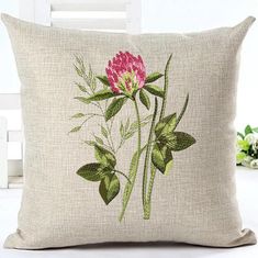 a pink flower on a beige pillow with green leaves