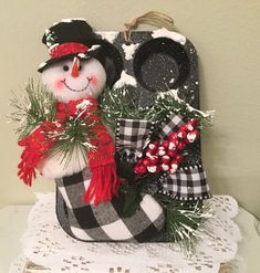 a snowman in a hat and scarf sitting on top of a table next to an oven mitt