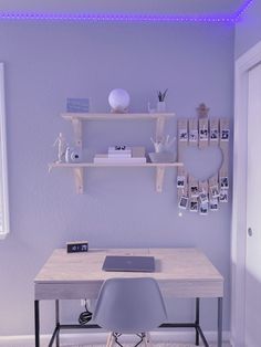 a desk with a laptop on top of it in front of a wall mounted shelf