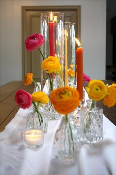 there are many vases with flowers and candles on the table