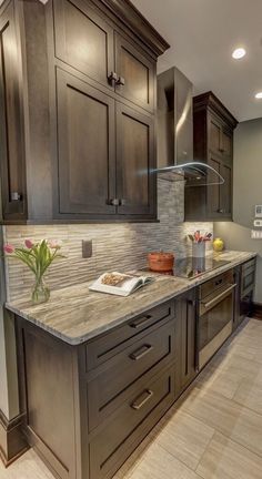 a kitchen with granite counter tops and dark wood cabinets, along with white tile flooring