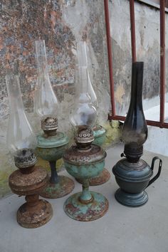 an assortment of vases sitting next to each other on a cement floor in front of a brick wall