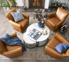 a living room with brown leather chairs and a white coffee table in front of a fireplace