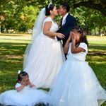 the bride and groom are posing for pictures with their children on their wedding day in the park