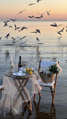 a couple of chairs sitting on top of a beach next to a table covered in food